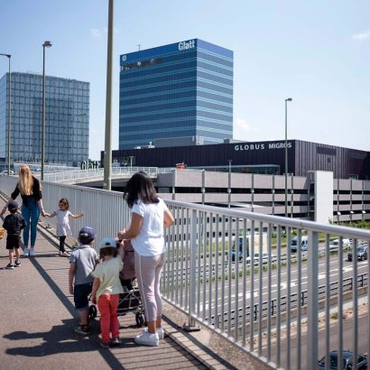 Betreuerinnen der Kinderkrippe Mikado gehen mit mehreren Kindern an der Hand über die Brücke zum Glatt-Zentrum